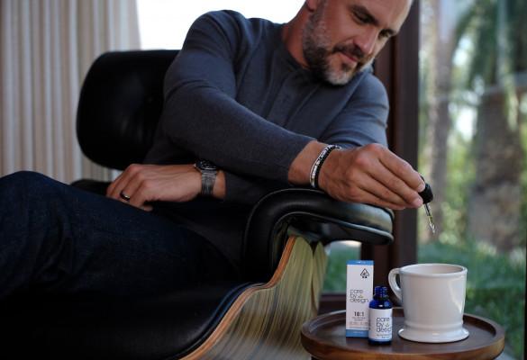 a man putting a cbd drop in a tea cup